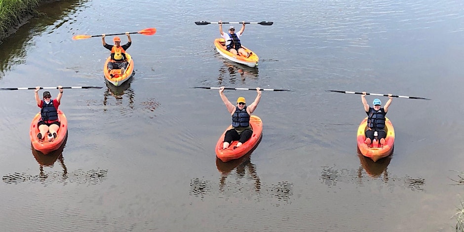 five kayakers in the water with paddles held above their heads
