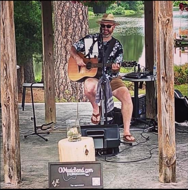 Chris Kelce playing guitar and singing in an outdoor setting