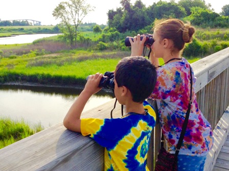 two kids with binoculars looking from a bridge