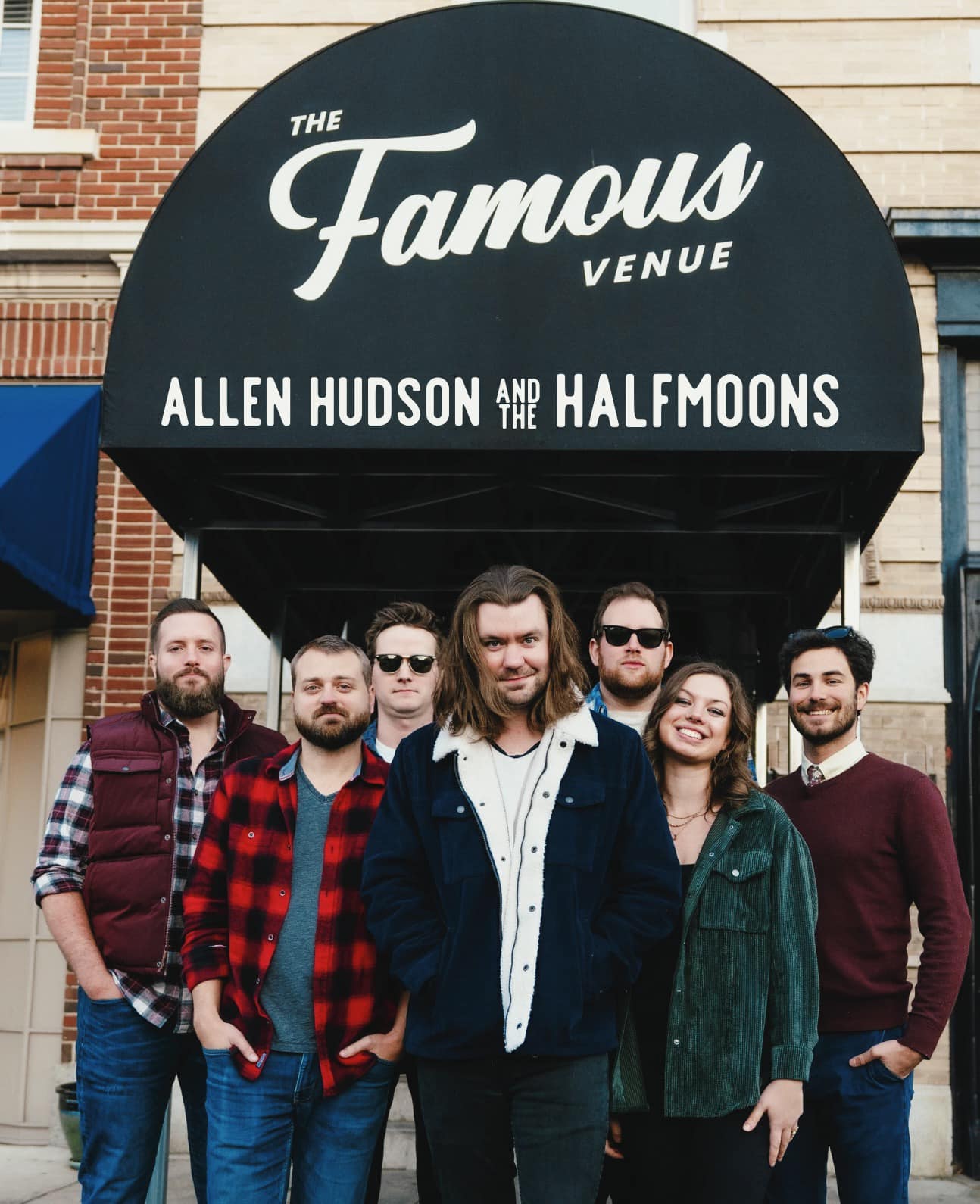 Band members standing outside The Famouse Venue Marquee