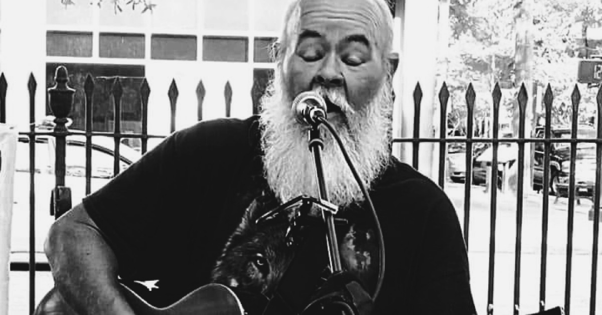 beared John Westbrook playing guitar and singing