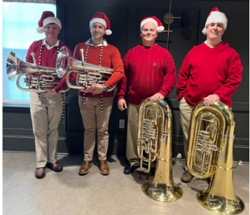 four men with tubas in Christmas dress