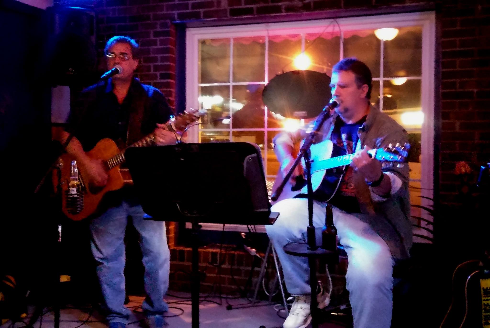 two men playing guitar and singing on stage